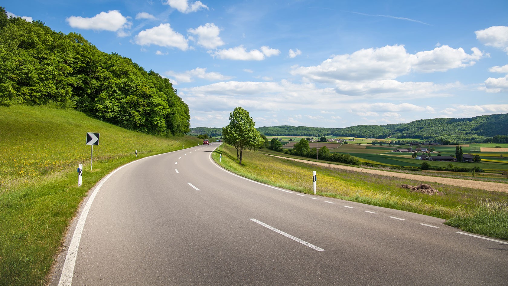 Country road surrounded by greenery with a blue sky.