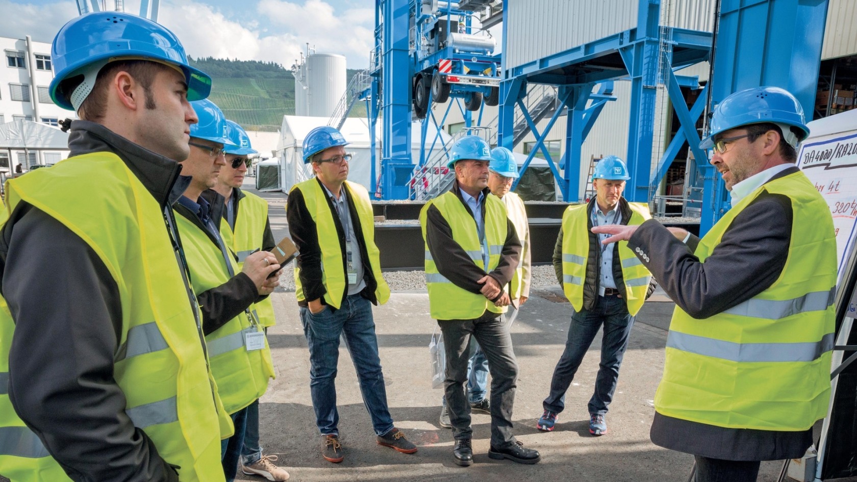 Training group with safety vests and blue helmets in front of Benninghoven plant