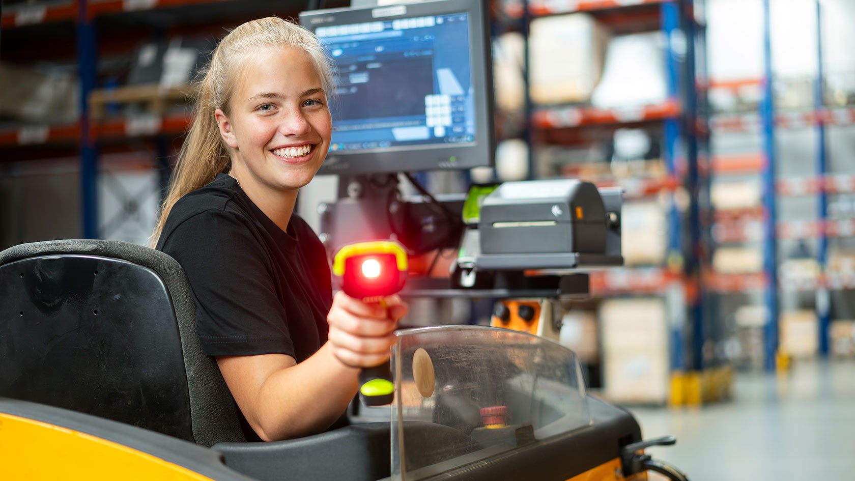 Laughing trainee in the warehouse on forklift truck