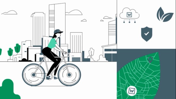 Woman riding a bicycle in front of a city skyline