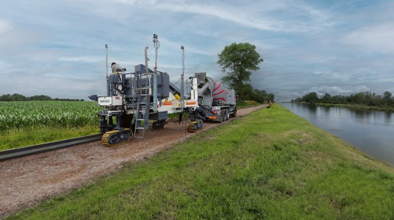 A slipform paver on a construction site by a river