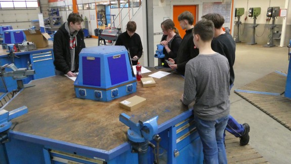 Schüler stehen um einen Tisch und schauen auf einen Plan.