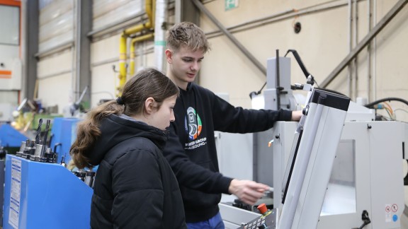 Männlicher Auszubildender erklärt Mädchen Maschine