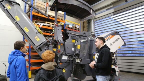 Mann erklärt zwei Jungen eine Wirtgen KLeinfräse W35Ri