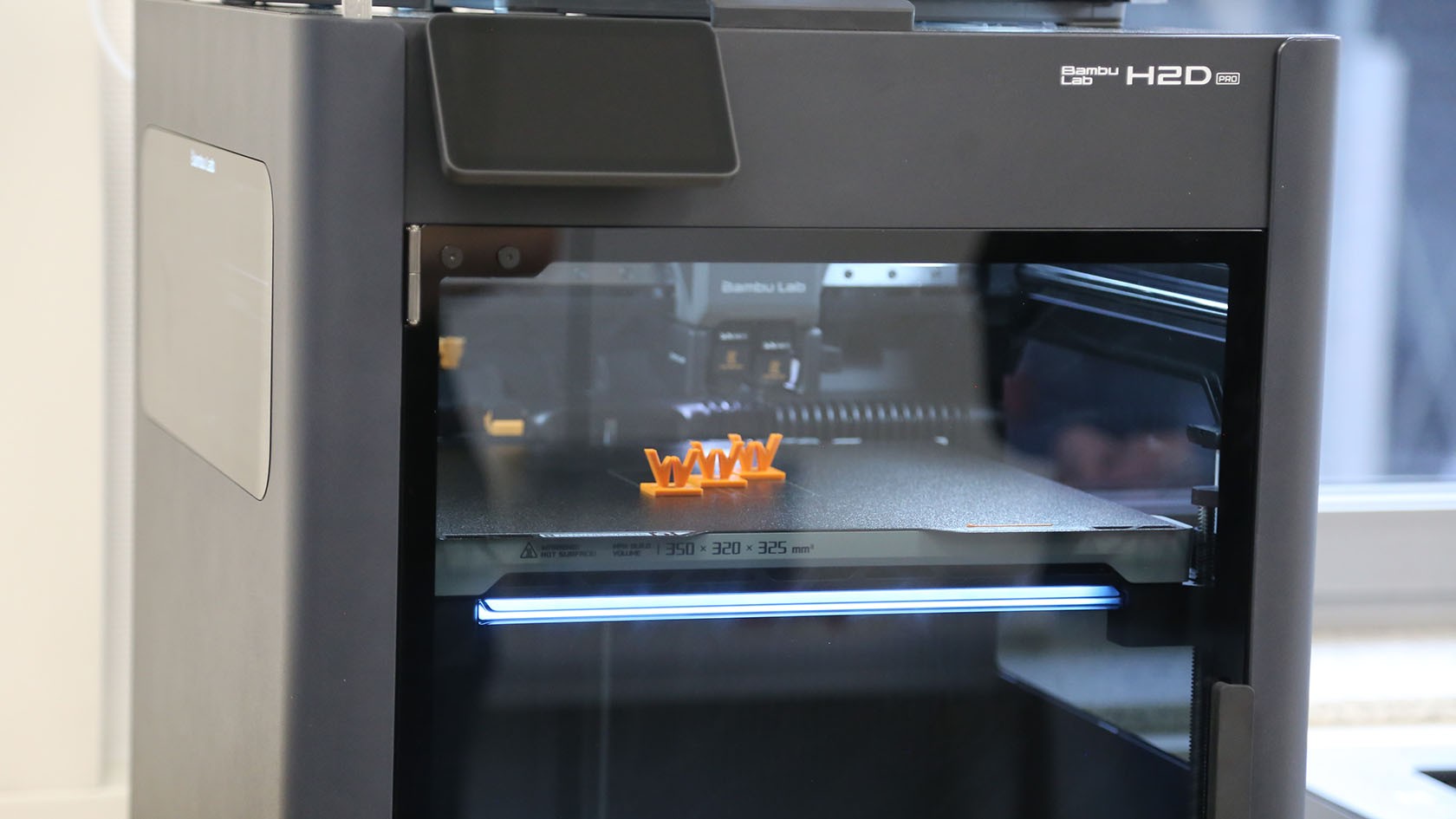 Drei kleine orangene Wirtgen Logos in einem 3D-Drucker