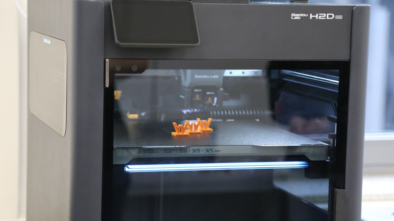 Drei kleine orangene Wirtgen Logos in einem 3D-Drucker