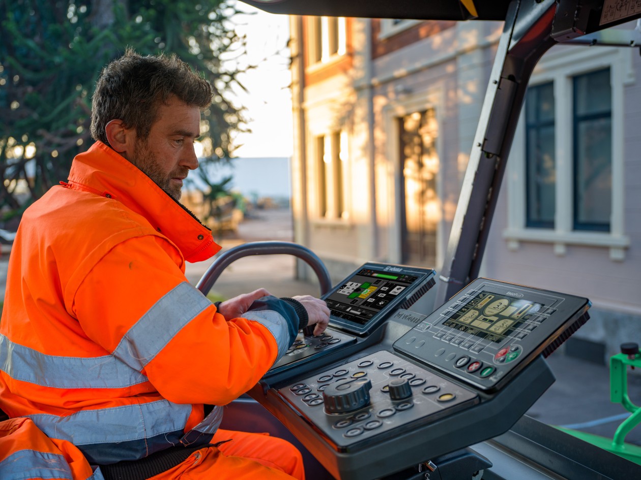The image shows a VÖGELE Dash 5 road paver, including operator with WPT paving on the ErgoPlus 5 Premium Touch Display.