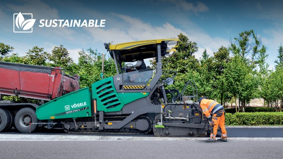 A SUPER 2100-5 X is paving a road under a blue sky and with trees in the background