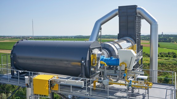 Burner on a hot gas generator with RAP drum against a green landscape