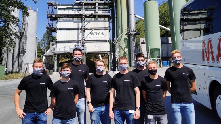 Gruppenfoto mit 8 neuen Azubis vor Asphaltmischanlage und Bus