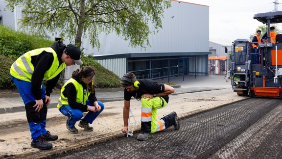 Trainees and an instructor measure the milling depth on the road.