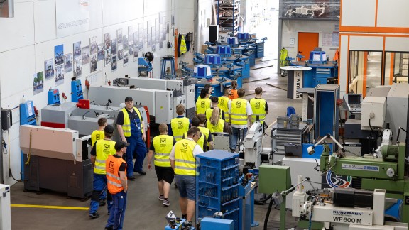A group of trainee participants walks through the factory hall