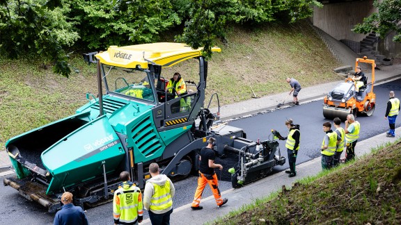 Bird’s eye view of a Vögele paver. Trainees watching the asphalt paving process.