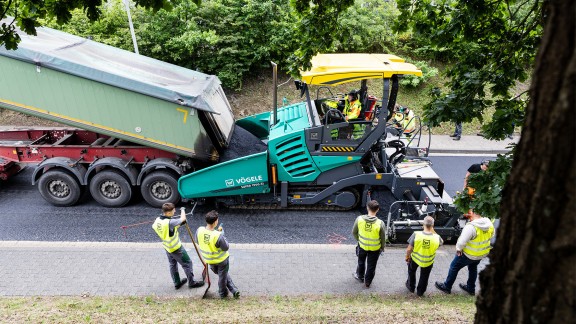 Trainees watch the asphalt paving process with a Vögele paver.