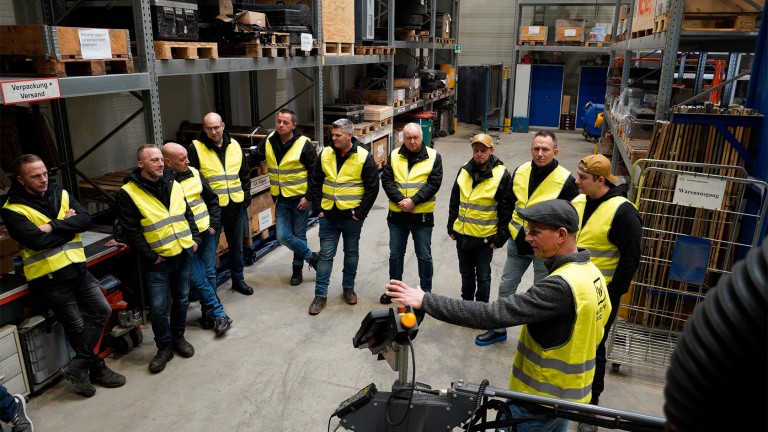 Group listening to an instructor in a storeroom.
