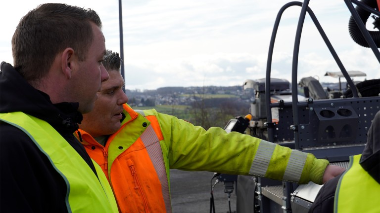 Screed operator Dominik Oberhauser (left) and paving supervisor Patrick Hänseler (right) being instructed on how to operate the screed. 