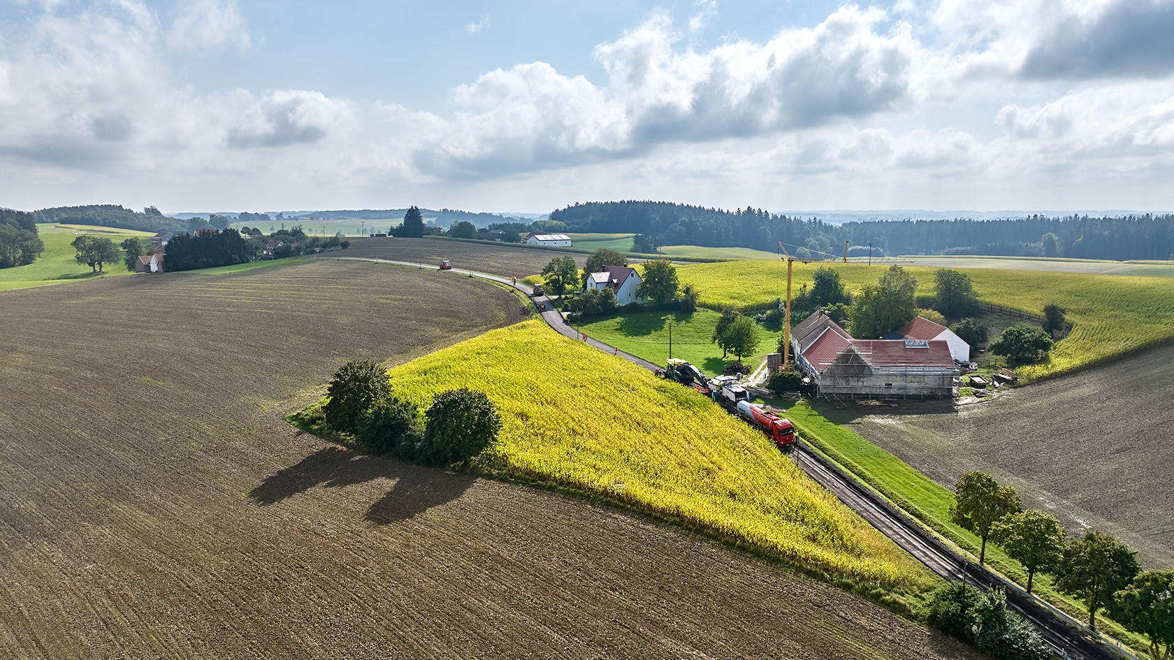 Bird’s eye view of the construction site in idyllic countryside with flowering fields of rape.