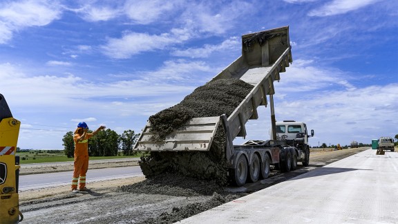 A tipper truck offloads concrete onto the sub-base