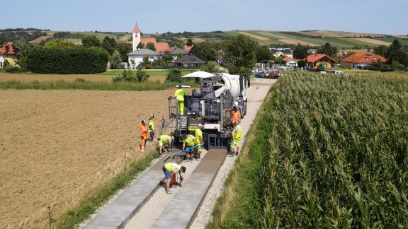 SP 33 in Sieghartskirchen, view of the construction site from the front, straight road between meadows and fields