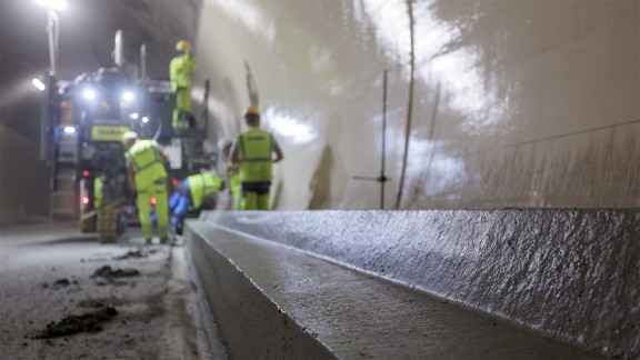 View of the paved kerb-gutter profile in the Semmering Tunnel with workers and the SP 33 in the background