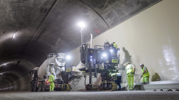 Paving kerb-gutter profiles in the Semmering Tunnel, two workers shovelling material in front of the SP 33.