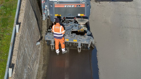 A worker standing in front of the sweeping unit of the W 210 XF.