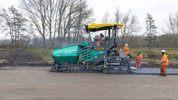Side view of paver with paving team.