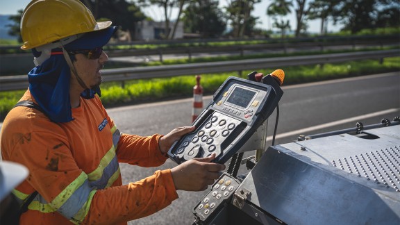 Worker operating the screed control unit on the operator’s platform.