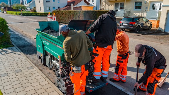 An operator standing on the MINI 502e next to three other construction workers.