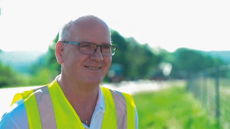 A middle-aged man looks to the right, smiling contentedly.