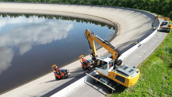 An excavator ensures the safety of the tandem rollers.