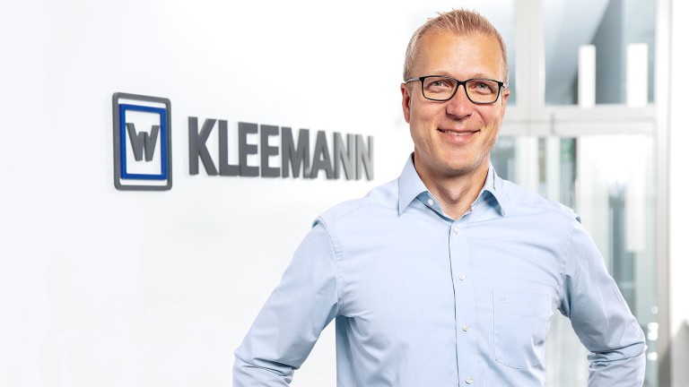 Man standing in front of Kleemann logo with a smile