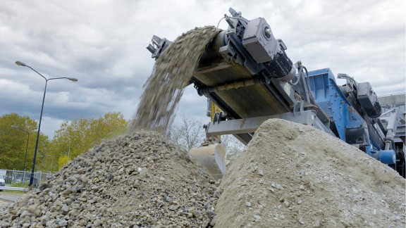 Discharge conveyor conveys processed material onto a stockpile.