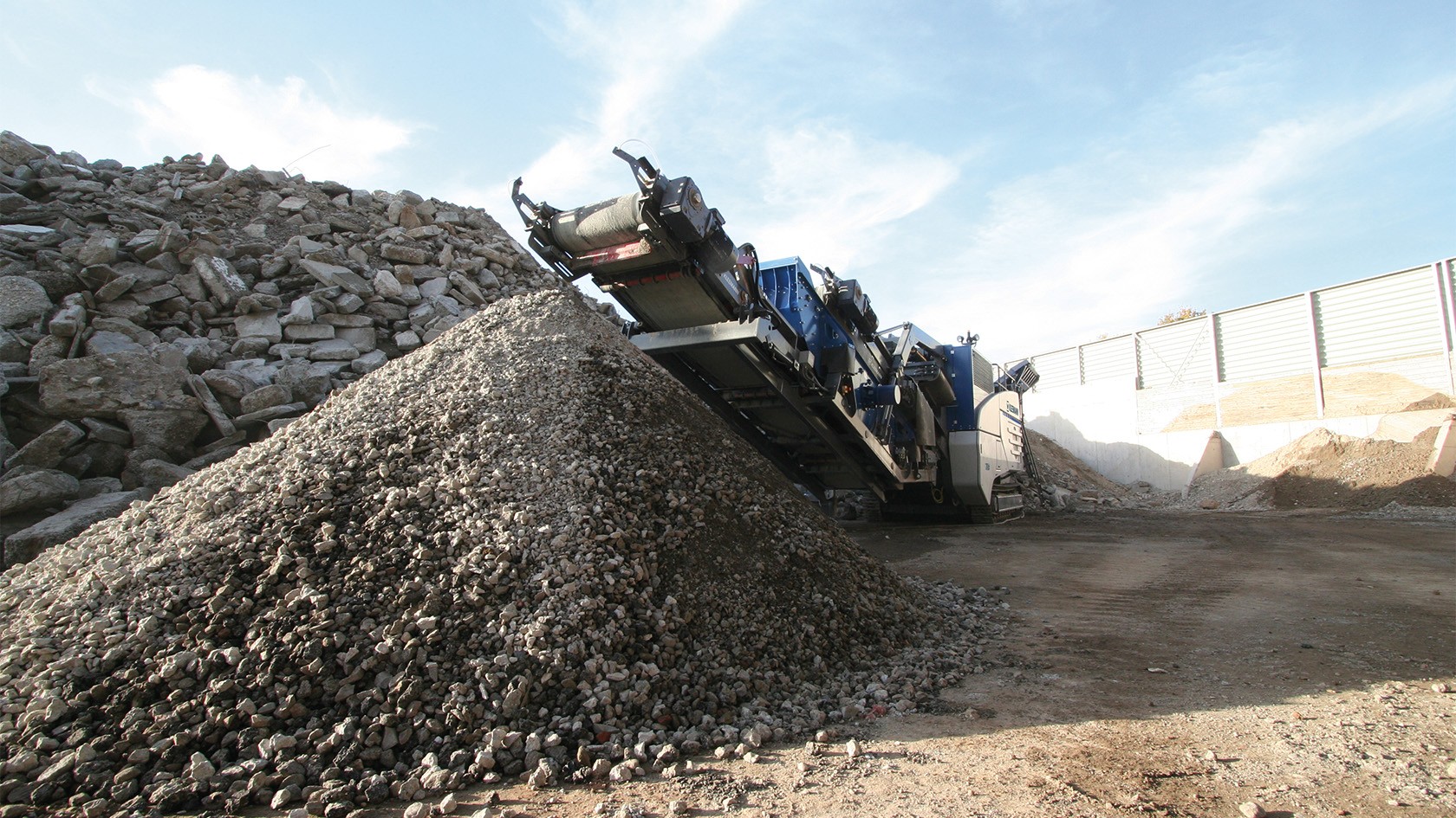 Dietro una montagna di materiali da costruzione riciclati si trova un impianto Kleemann