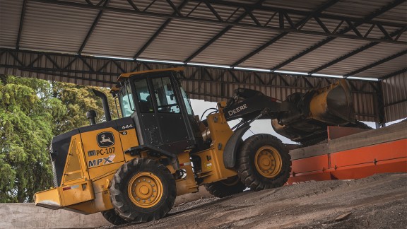 John Deere front loader loads mixed product into the Ciber asphalt mixing plant.