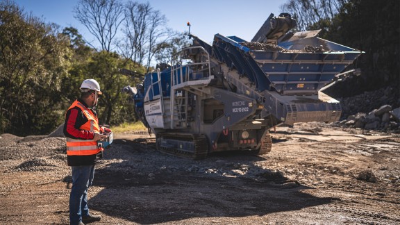 Employee in the quarry operating cone crusher with a radio remote control.