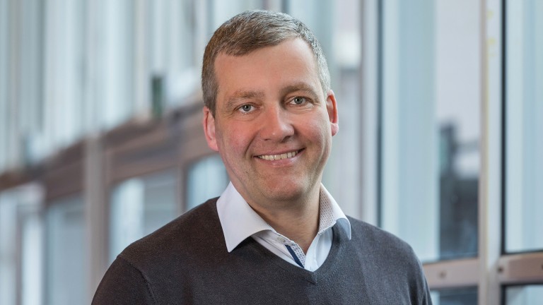 Un gentiluomo di mezza età sorride alla telecamera.