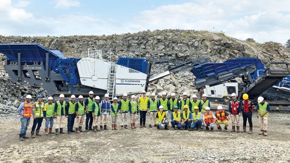 A group photo of employees of PT. Bukit Asam Tbk. in the mine in front of two Kleemann crushing plants.