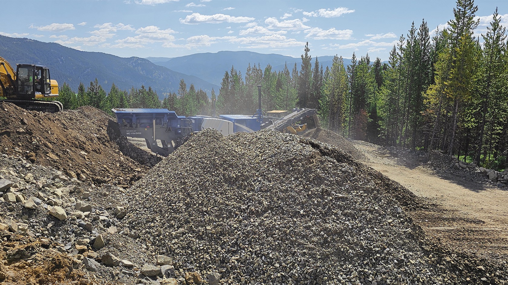 MOBICAT MC 110i EVO2 behind a pile of already processed rock.