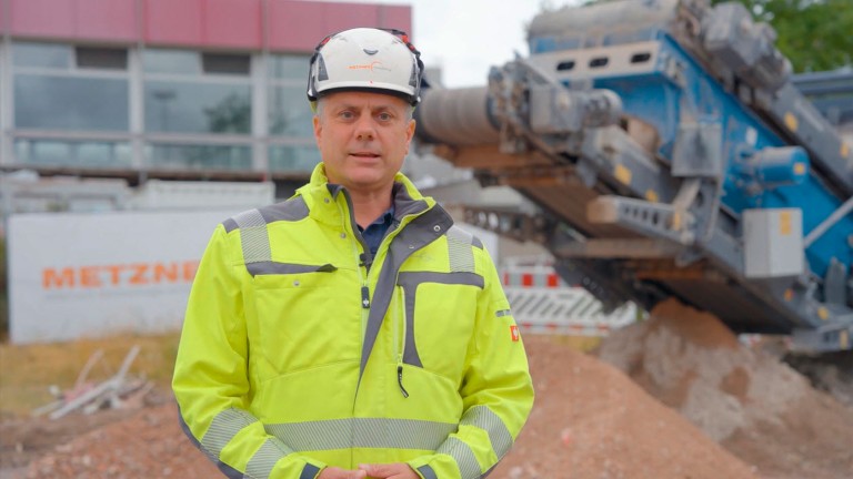 Hombre vestido de obra delante de una instalación trituradora de Kleemann