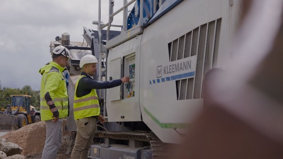 Dos hombres vestidos de obra miran el sistema de control de la instalación trituradora.