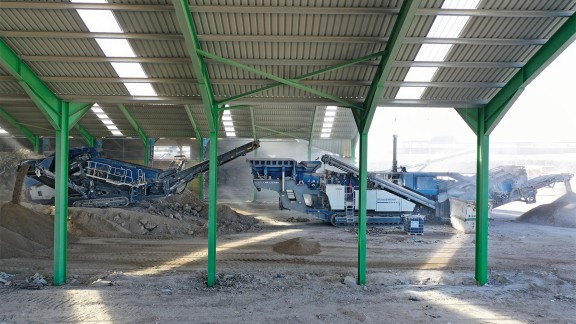Impact crusher standing in the shade of a canopy.