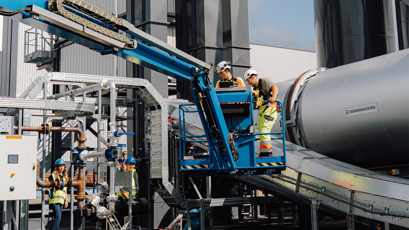Two trainees on a crane in the midst of the CORE plant, with the burner on the right.