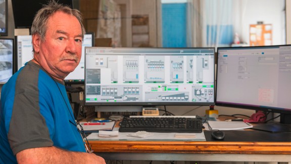 User in front of a computer screen, looking at the camera.