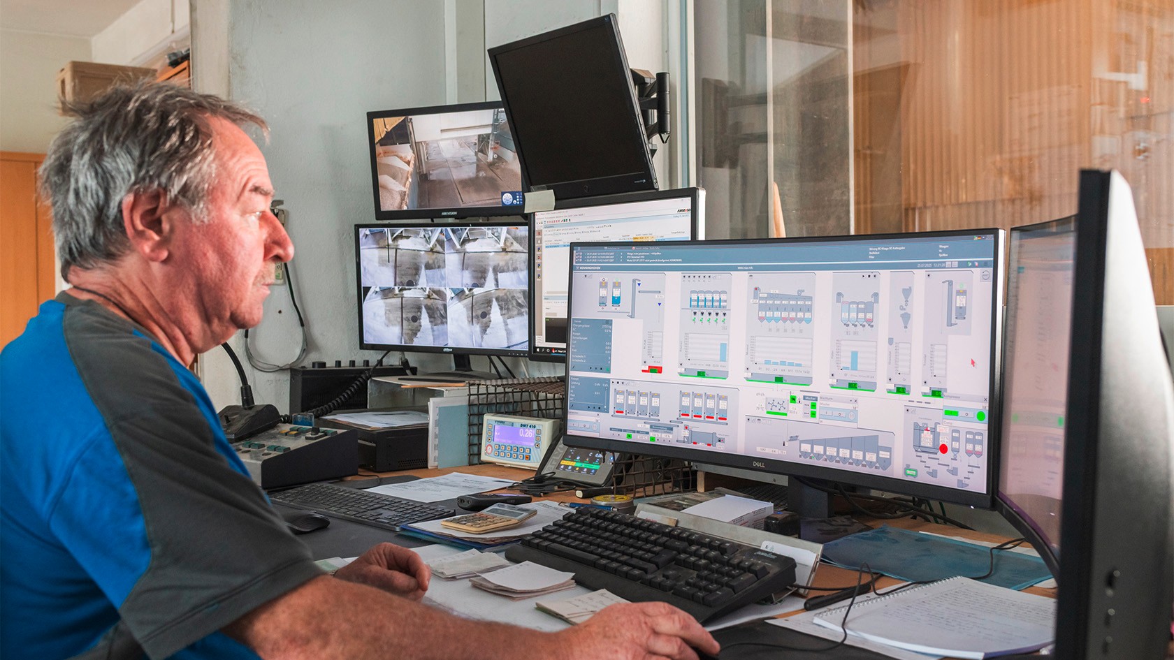 Side view of the mixing foreman sitting at a computer, looking at the control functions on the screen.
