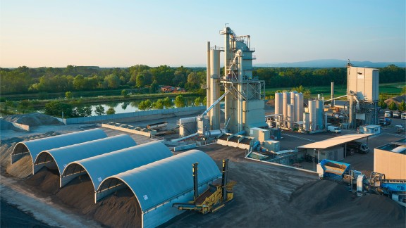 Asphalt mixing plant with a covered material storage areas in the foreground