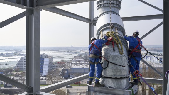 Two people position the tube for the exhaust gas on the plant.