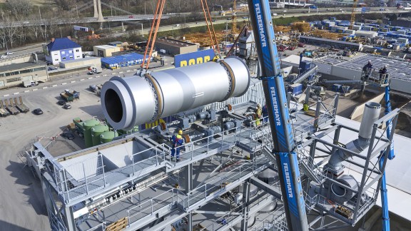The recycling drum is suspended from the crane above the plant.