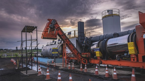 La centrale d’enrobage au coucher du soleil. Une bande de chargement en gros plan.